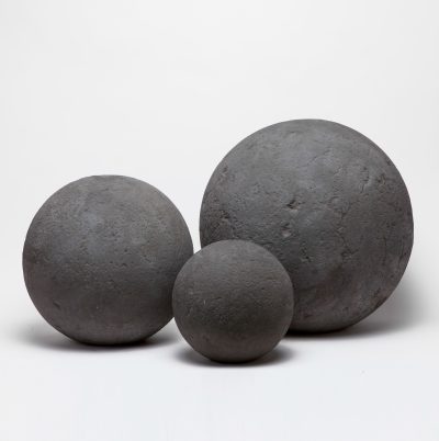 Three large, dark gray concrete balls on a white surface.