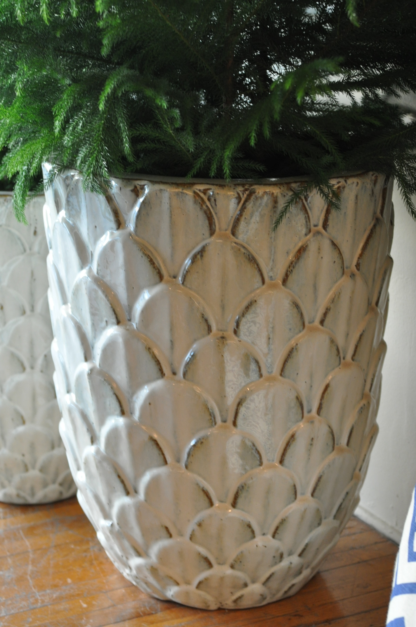 Large white vase with a pine cone design, placed on a wooden surface.