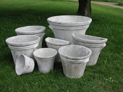 A collection of five concrete planters in various sizes, displayed outdoors on grass.